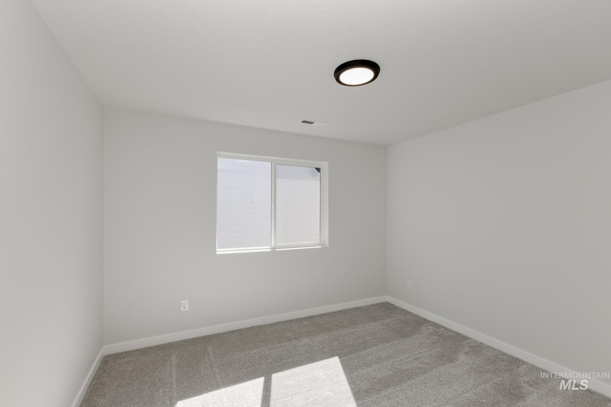 Carpeted spare room with baseboards