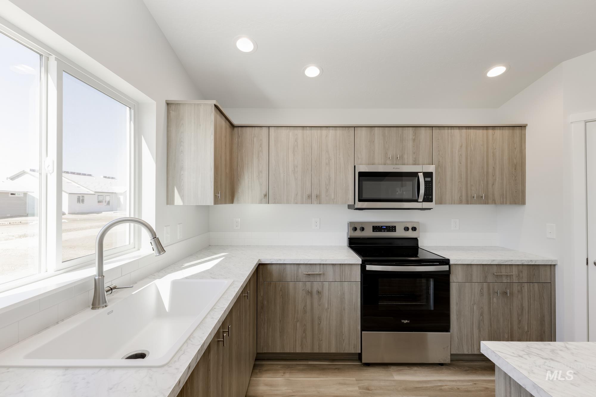 Kitchen featuring appliances with stainless steel finishes, light wood-style flooring, recessed lighting, modern cabinets, and light stone countertops