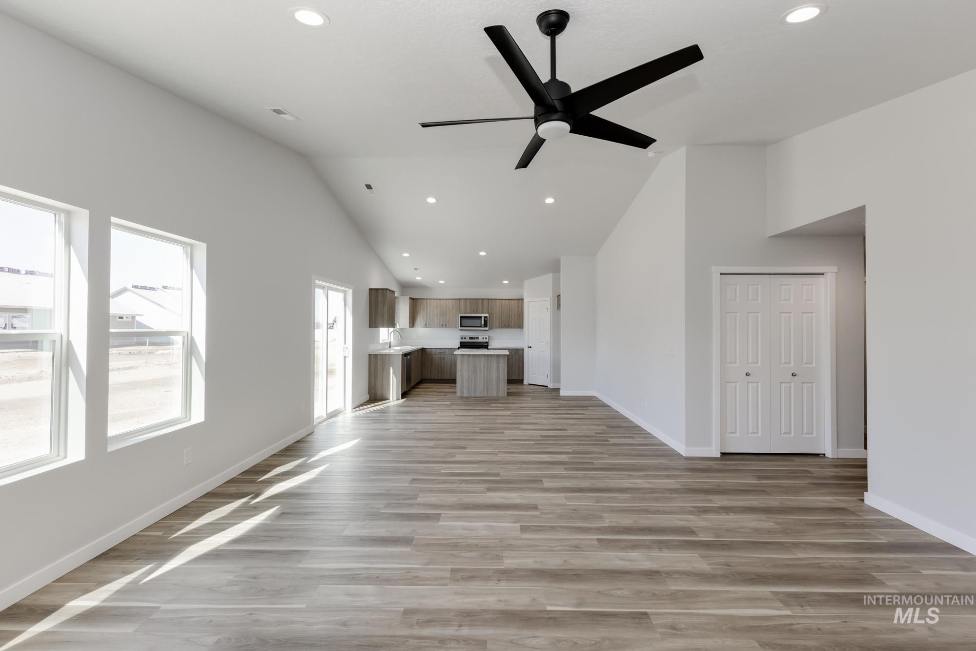 Unfurnished living room with recessed lighting, light wood finished floors, a ceiling fan, and high vaulted ceiling