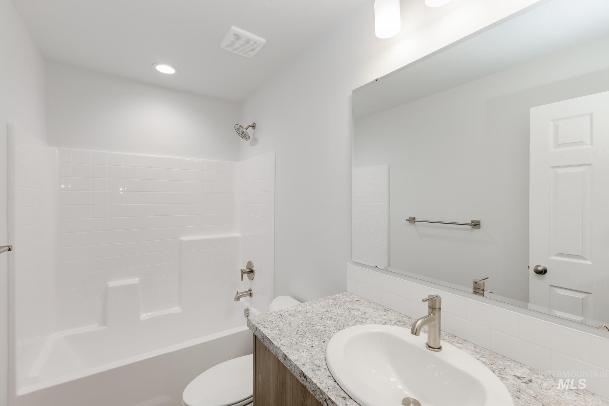 Bathroom featuring tub / shower combination, vanity, and recessed lighting