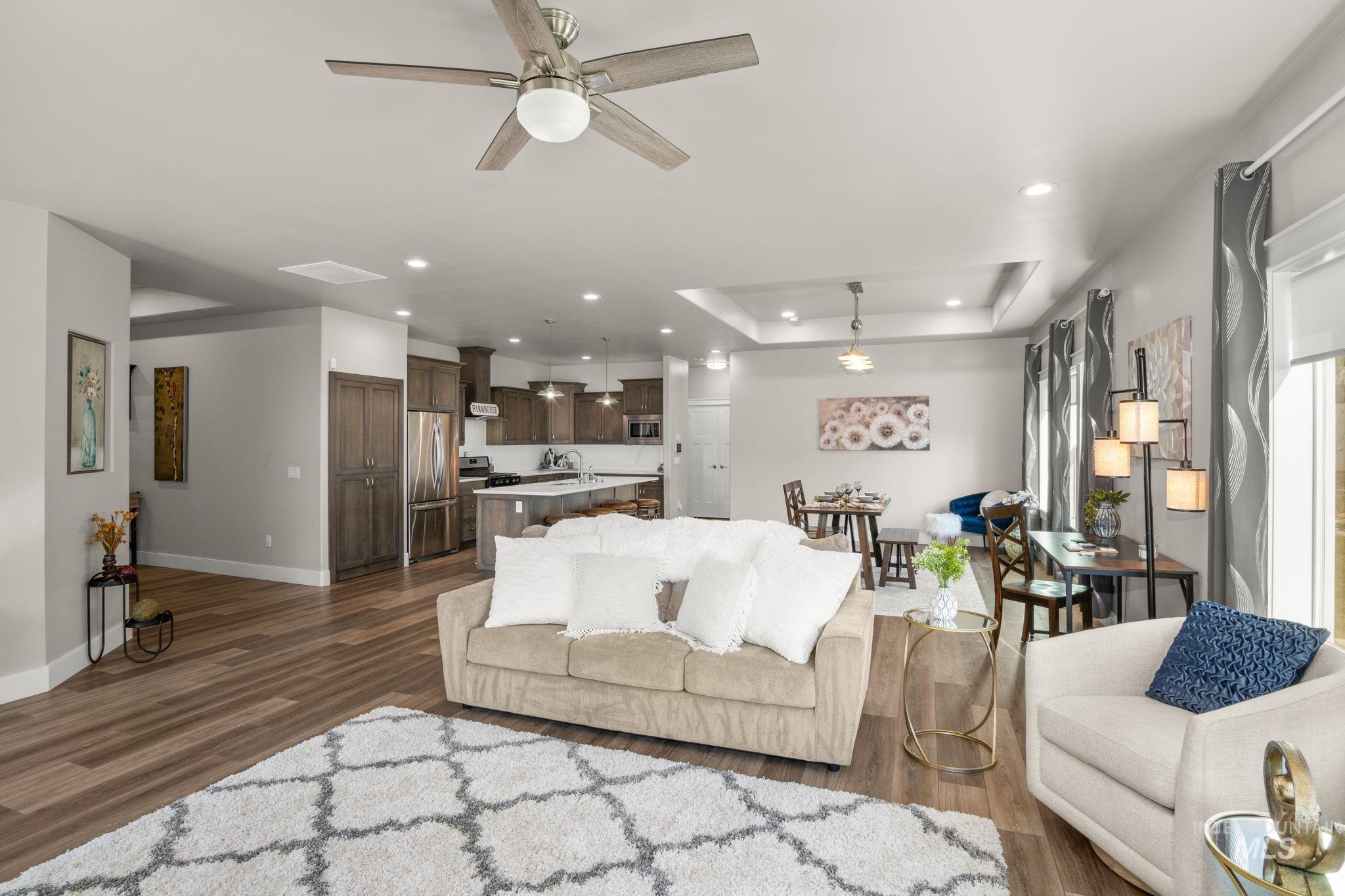 Living room with ceiling fan, dark wood-style floors, a raised ceiling, and recessed lighting