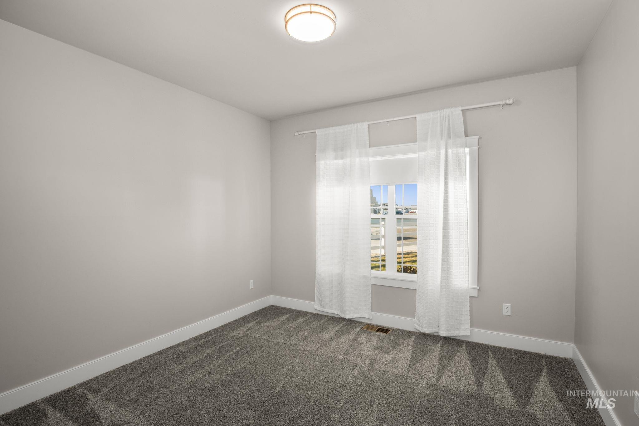 Unfurnished room featuring baseboards and dark carpet