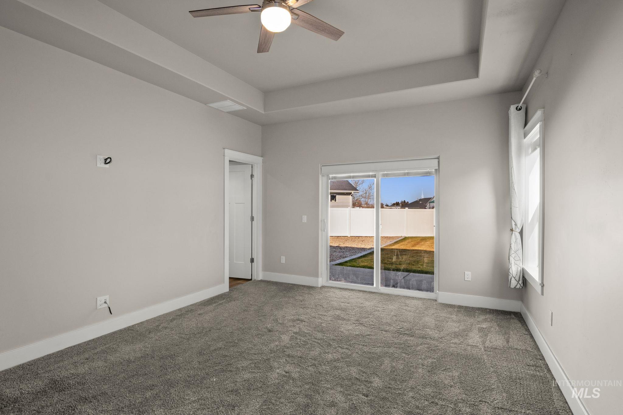 Unfurnished room with a raised ceiling, carpet floors, and a ceiling fan