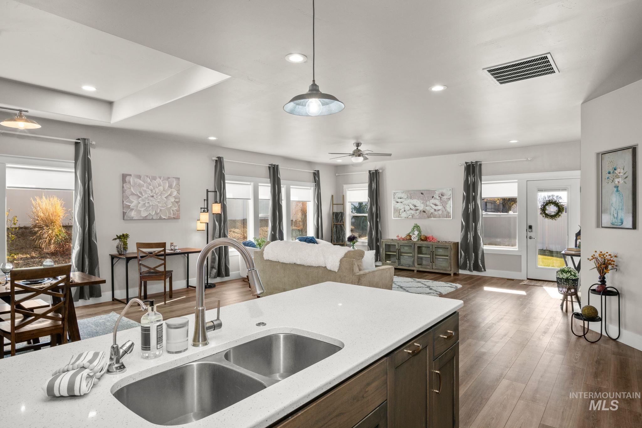 Kitchen with light stone countertops, dark wood-type flooring, hanging light fixtures, dark brown cabinetry, and recessed lighting