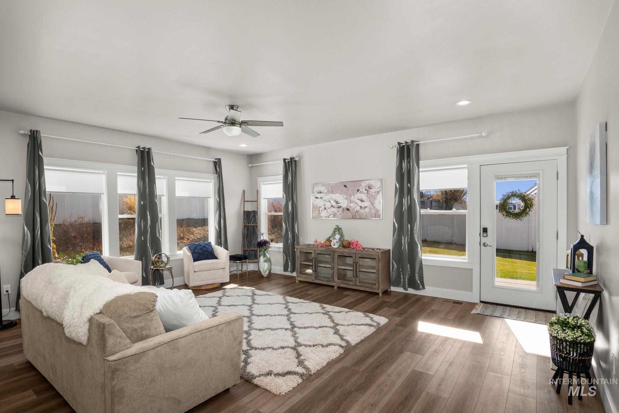 Living room with ceiling fan, healthy amount of natural light, and dark wood-style flooring