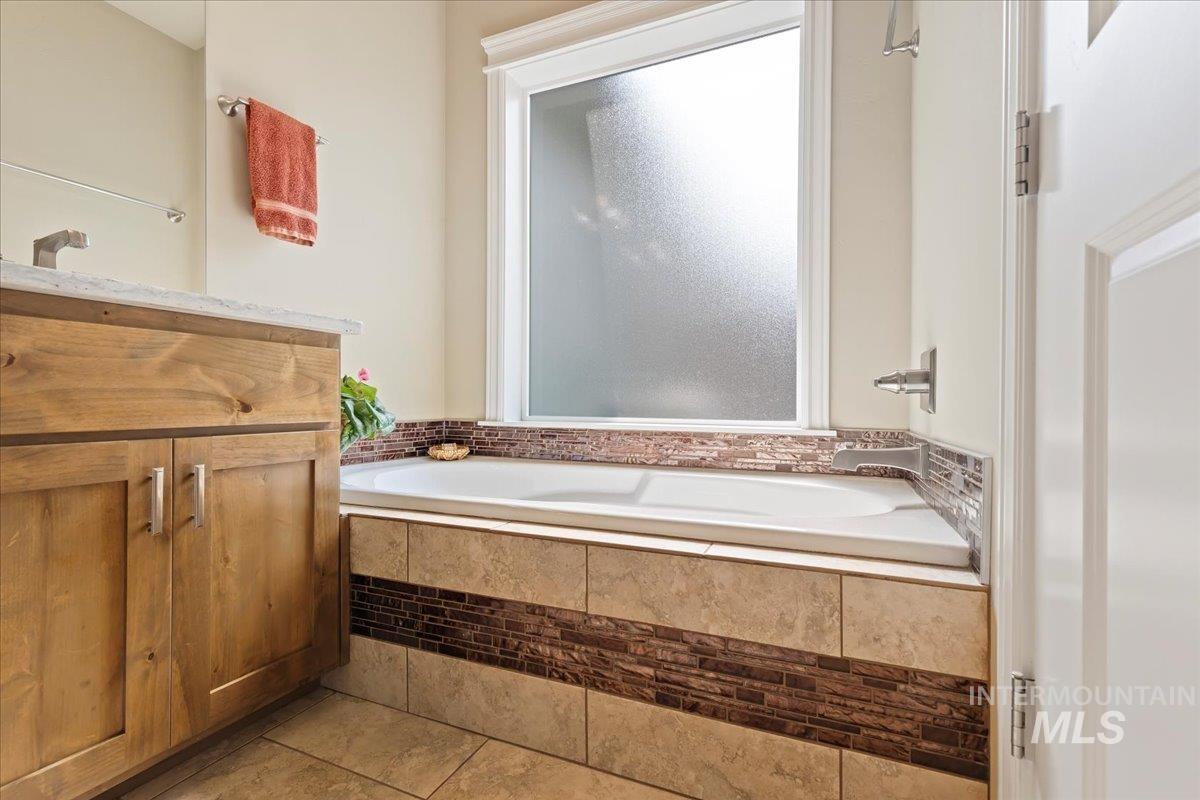 Bathroom featuring a garden tub, vanity, and tile patterned floors