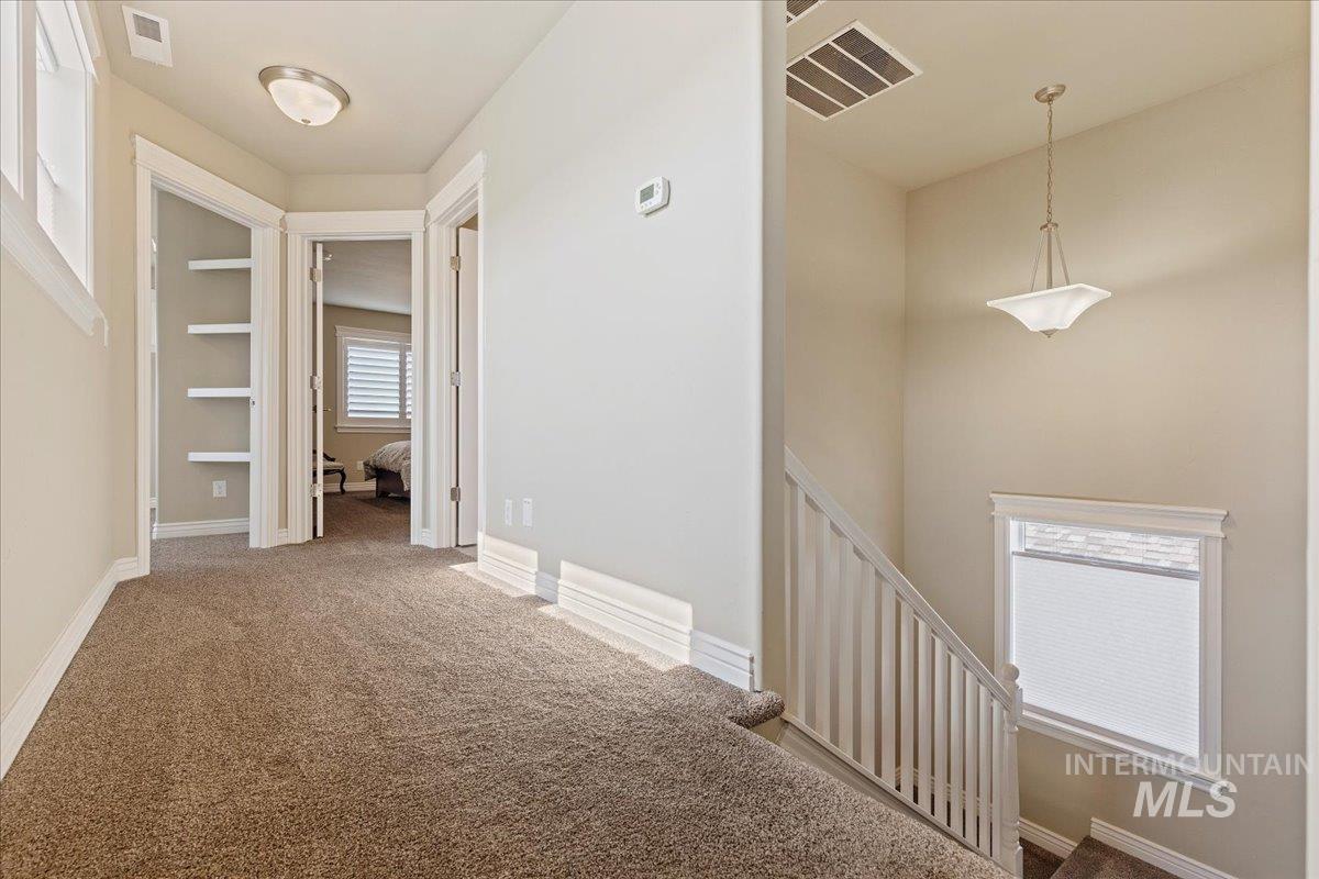 Corridor featuring an upstairs landing and carpet