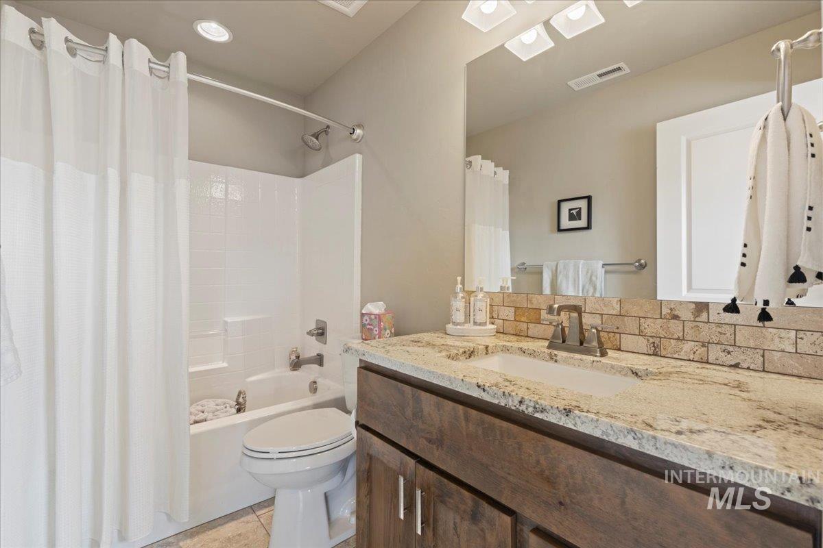 Bathroom featuring vanity, shower / tub combo with curtain, and tile patterned floors