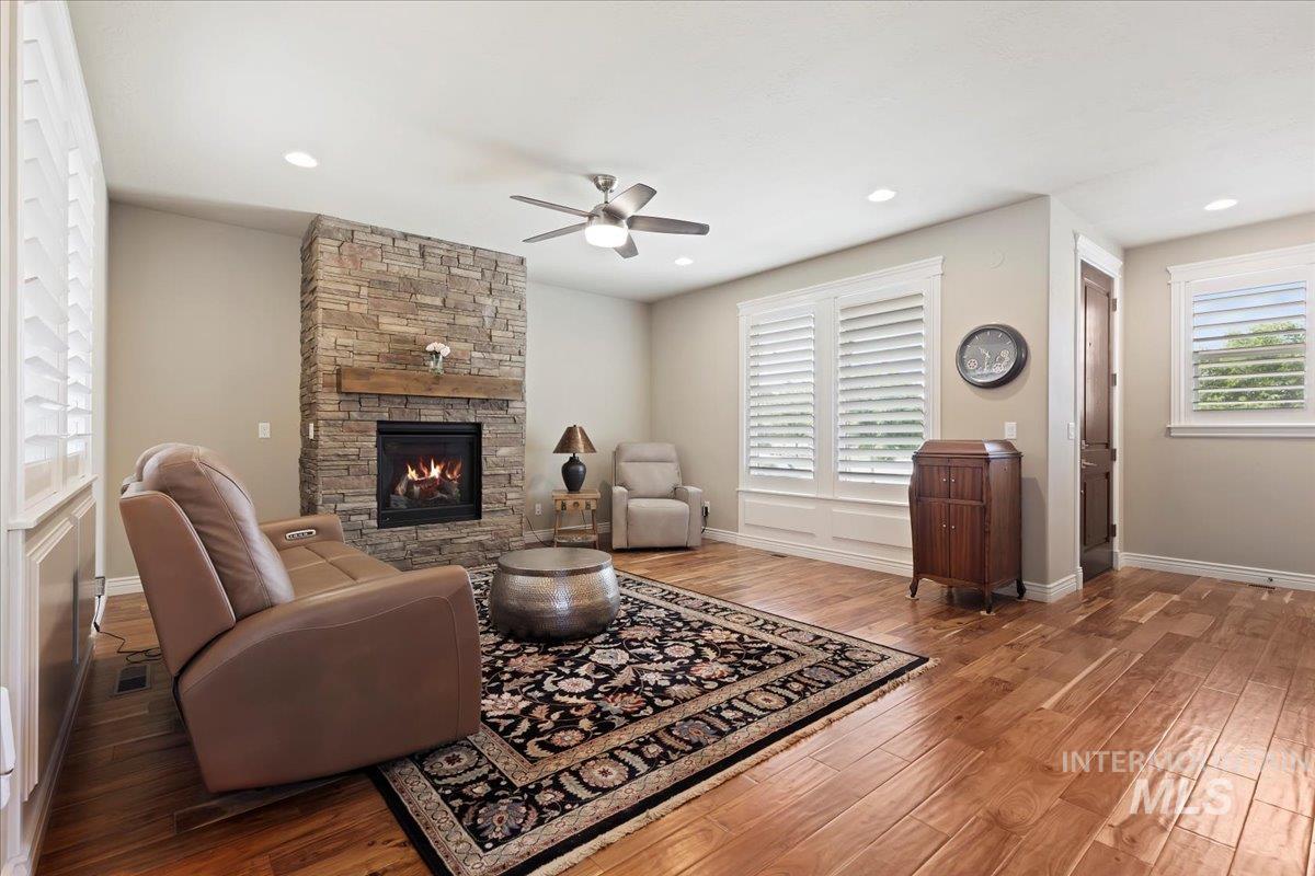 Living room with a ceiling fan, a fireplace, wood finished floors, and recessed lighting