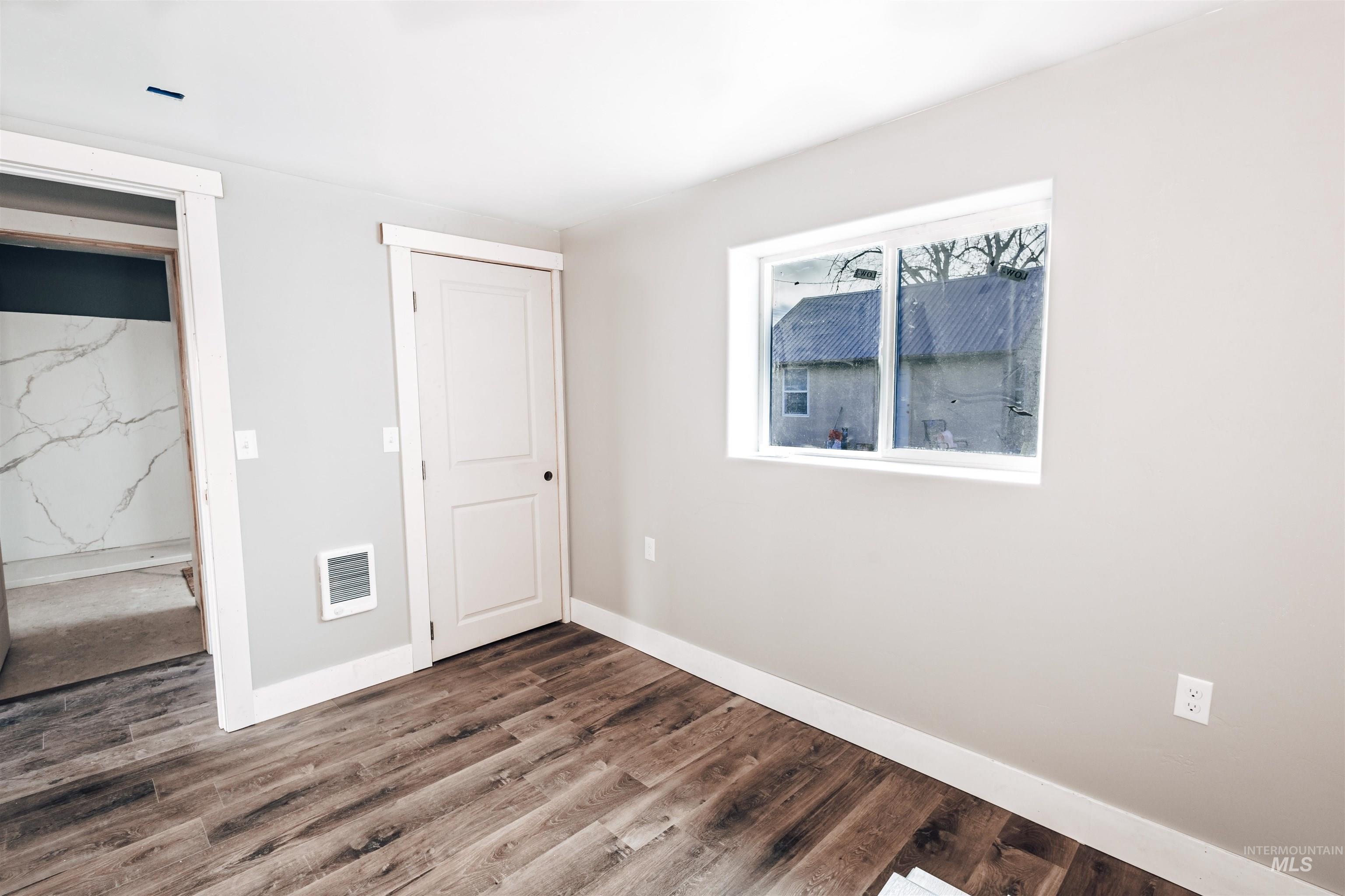 Unfurnished bedroom featuring dark wood finished floors and baseboards