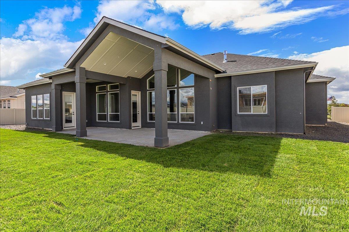 Back of house with stucco siding, a patio area, and roof with shingles