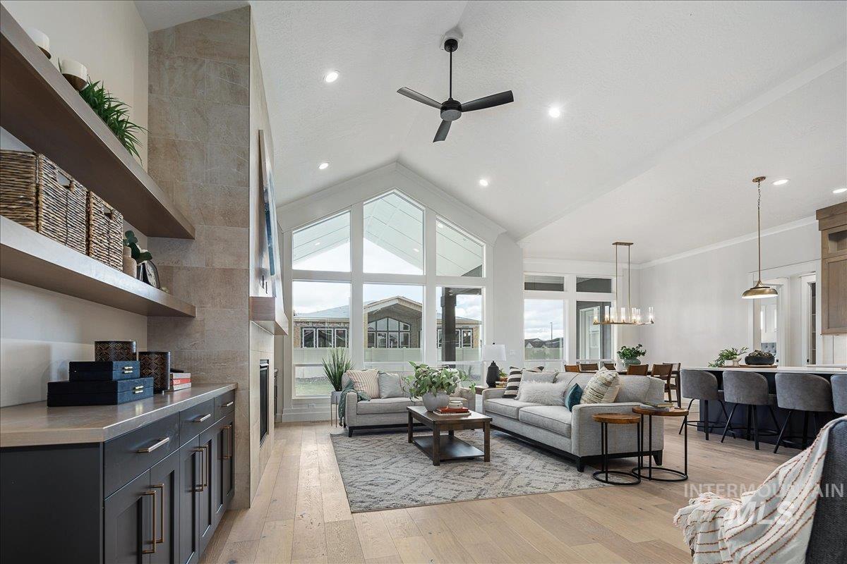 Living area featuring light wood-type flooring, high vaulted ceiling, a ceiling fan, and crown molding