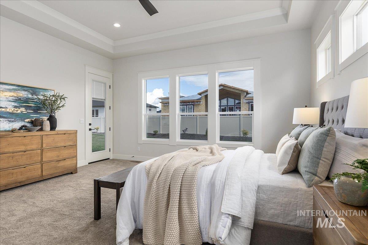 Carpeted bedroom with a raised ceiling, a ceiling fan, and access to outside