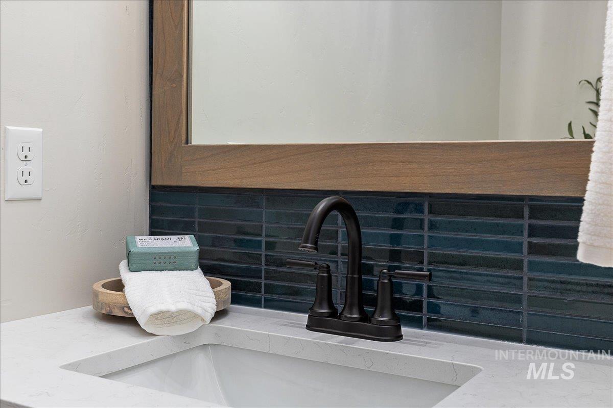 Bathroom view of vanity, tasteful backsplash, and a textured wall