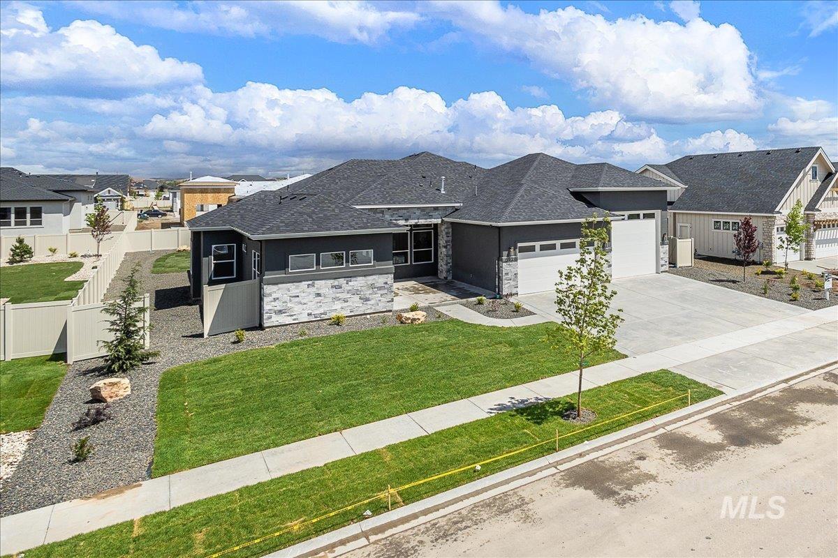 View of front of property featuring stone siding, driveway, a garage, and roof with shingles