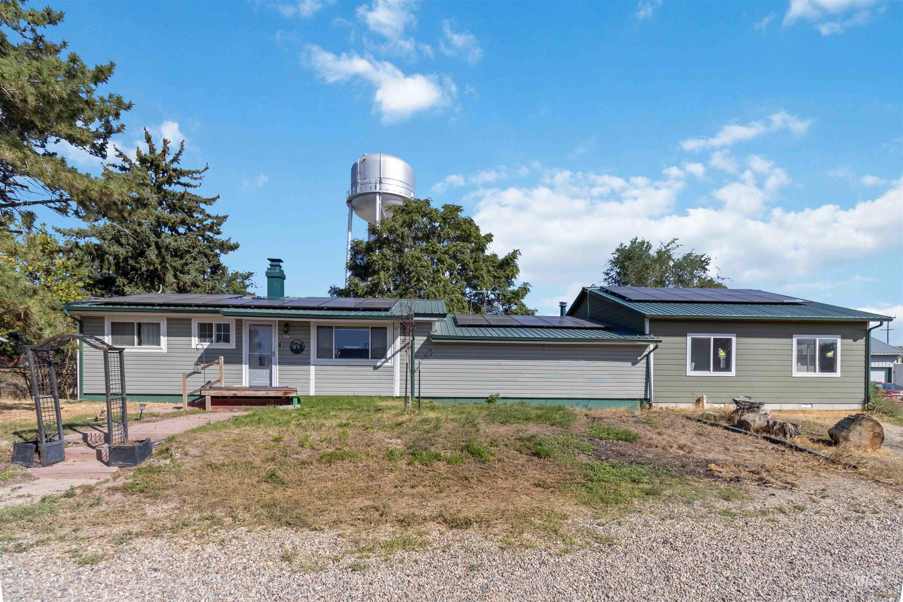 View of front of home featuring solar panels, a chimney, and a metal roof