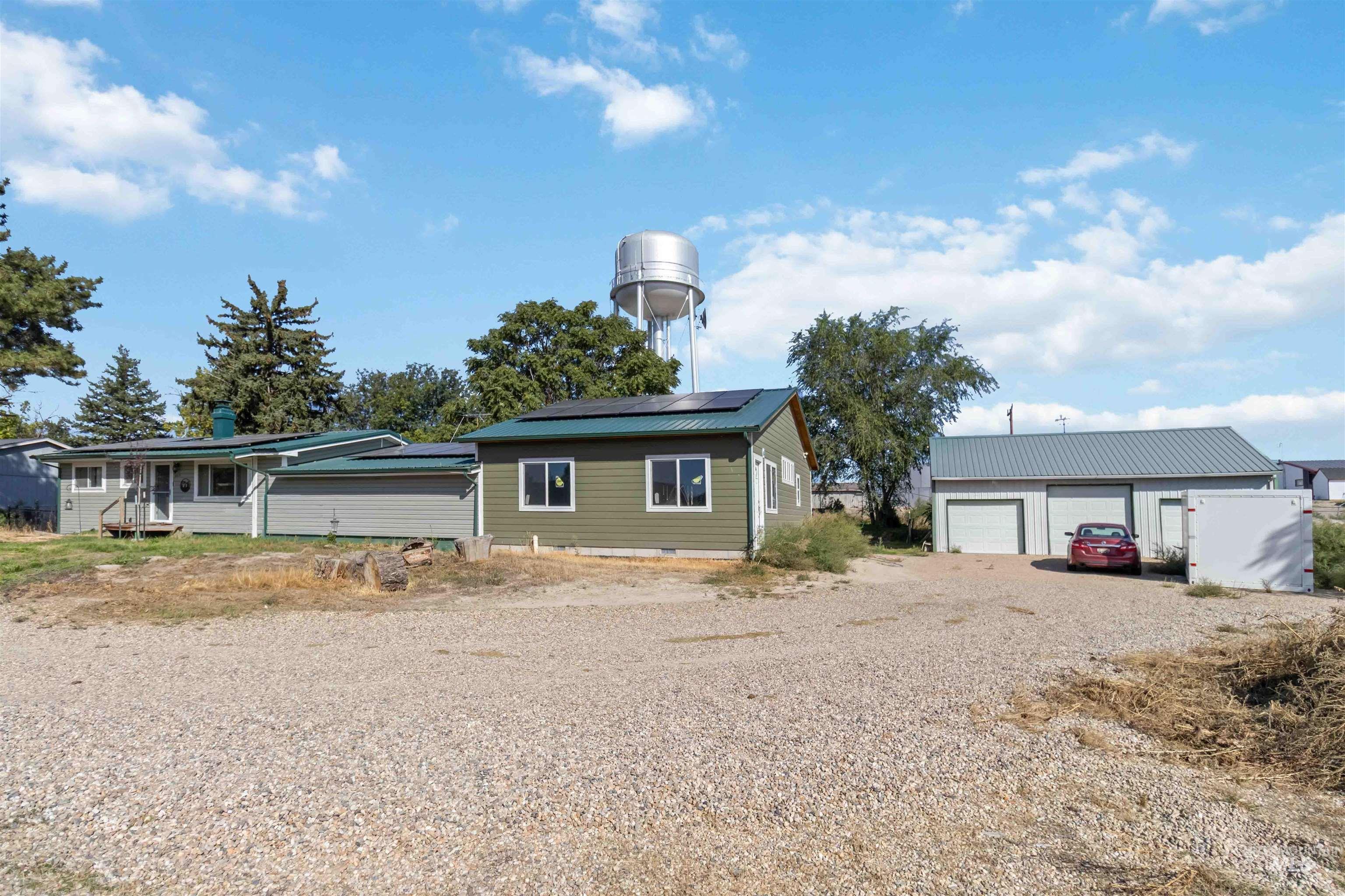 View of front of property with an outdoor structure, roof mounted solar panels, and a detached garage