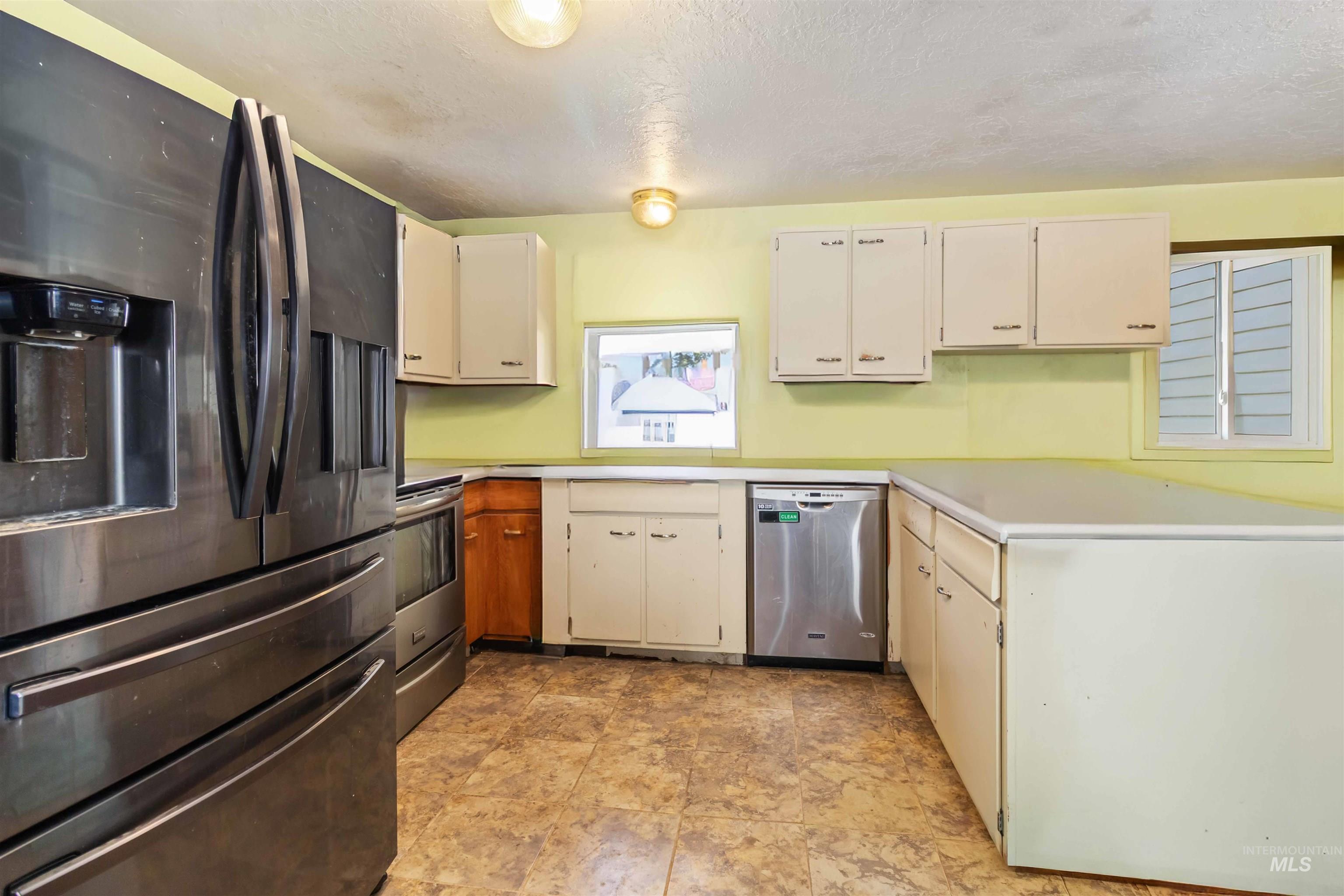 Kitchen with stainless steel appliances, light countertops, a peninsula, and a textured ceiling