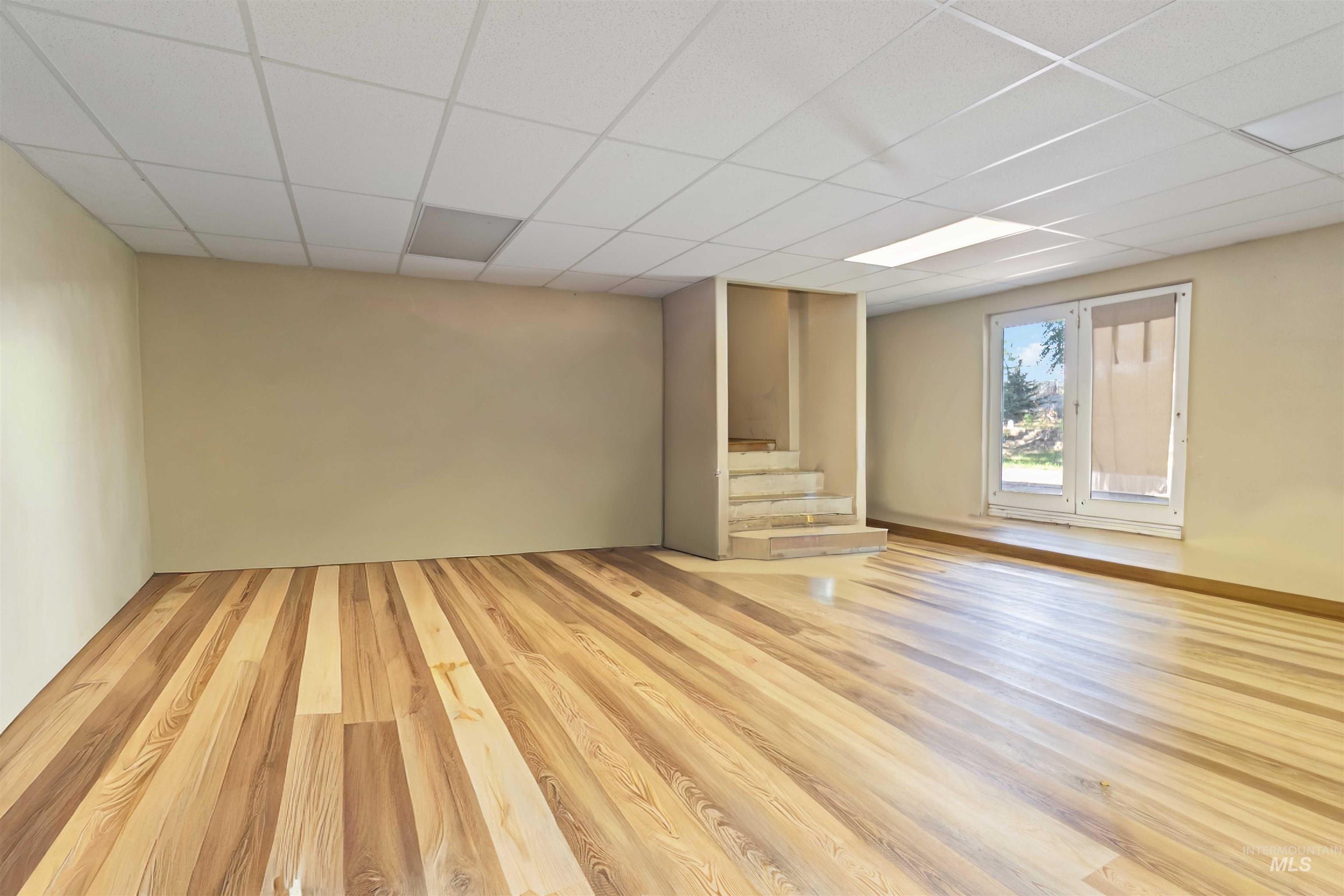 Basement with wood finished floors, a paneled ceiling, and stairs