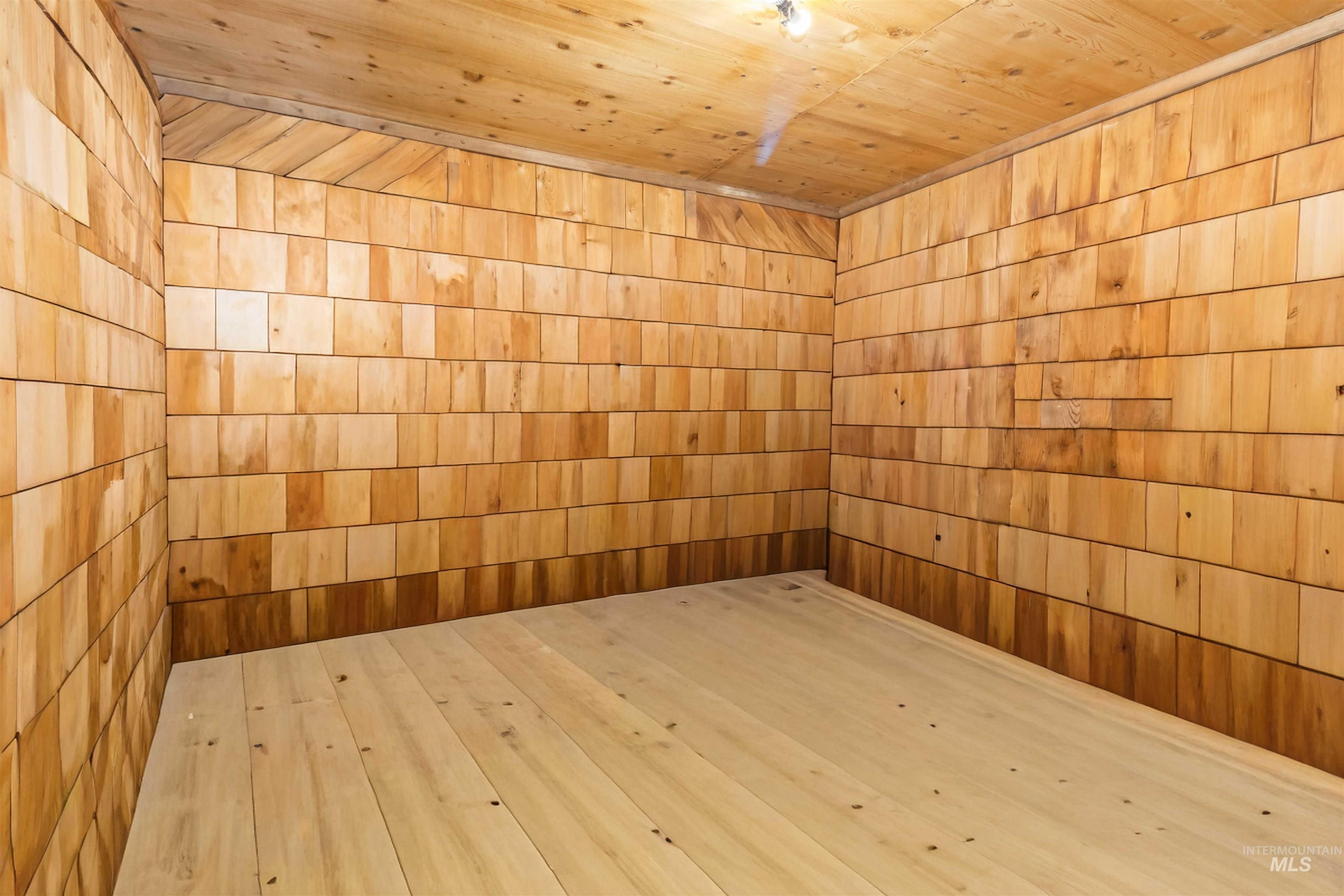 Unfurnished room with a sauna, wooden ceiling, hardwood / wood-style flooring, and wood walls