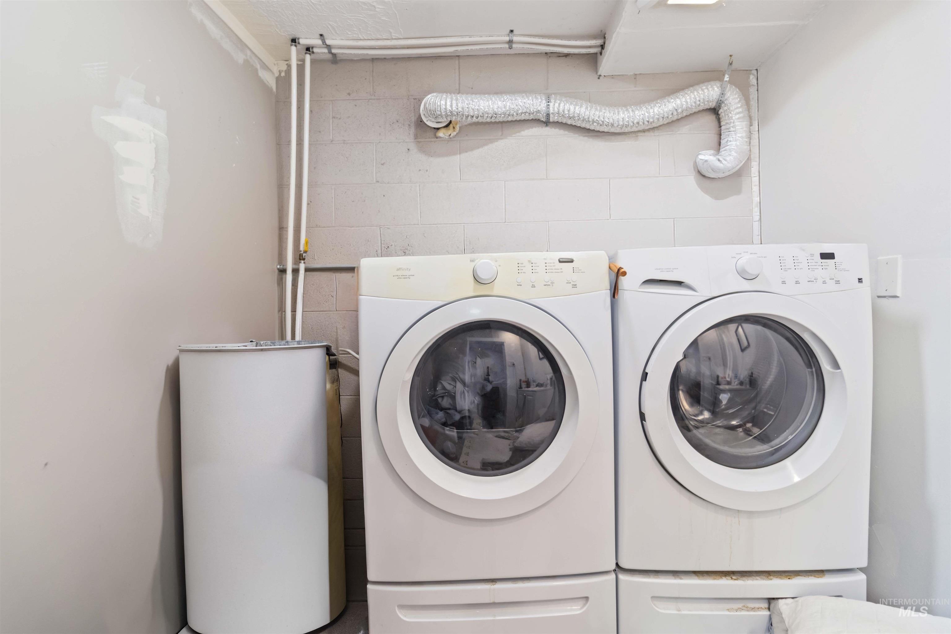 Laundry area featuring concrete block wall and washer and dryer