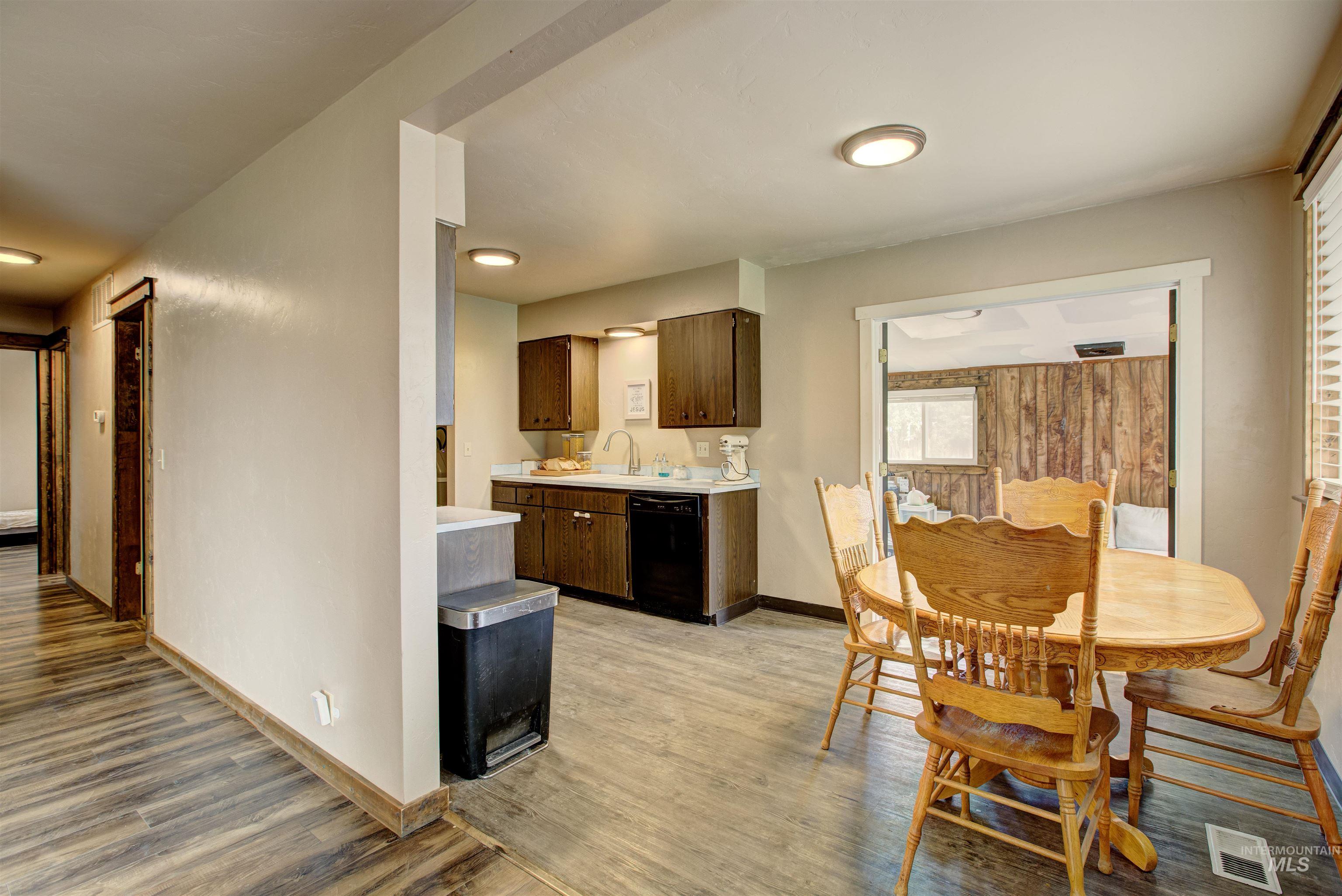 Kitchen featuring light countertops, dark brown cabinets, black dishwasher, and light wood-type flooring