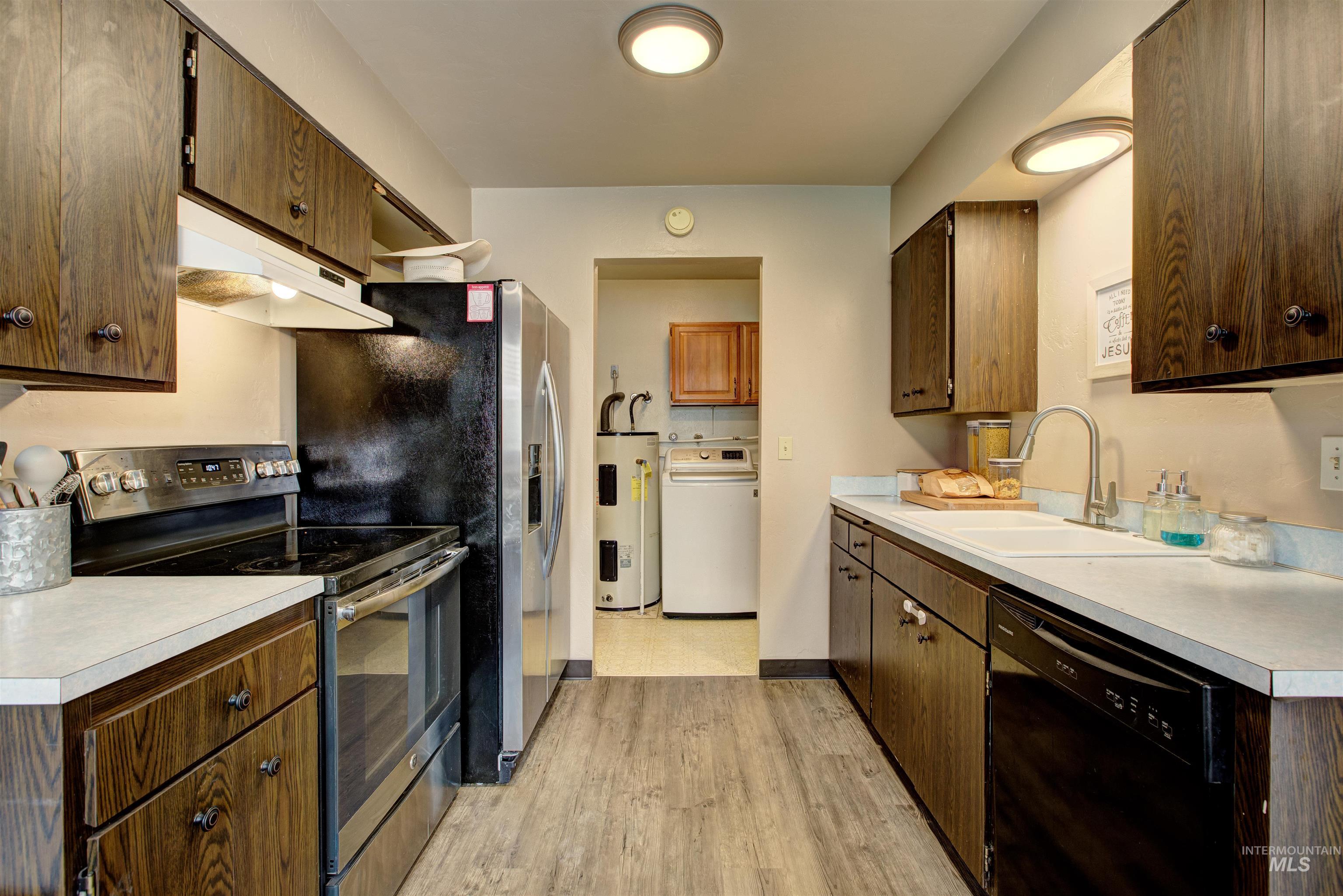 Kitchen with stainless steel electric range, dishwasher, washer / clothes dryer, under cabinet range hood, and electric water heater