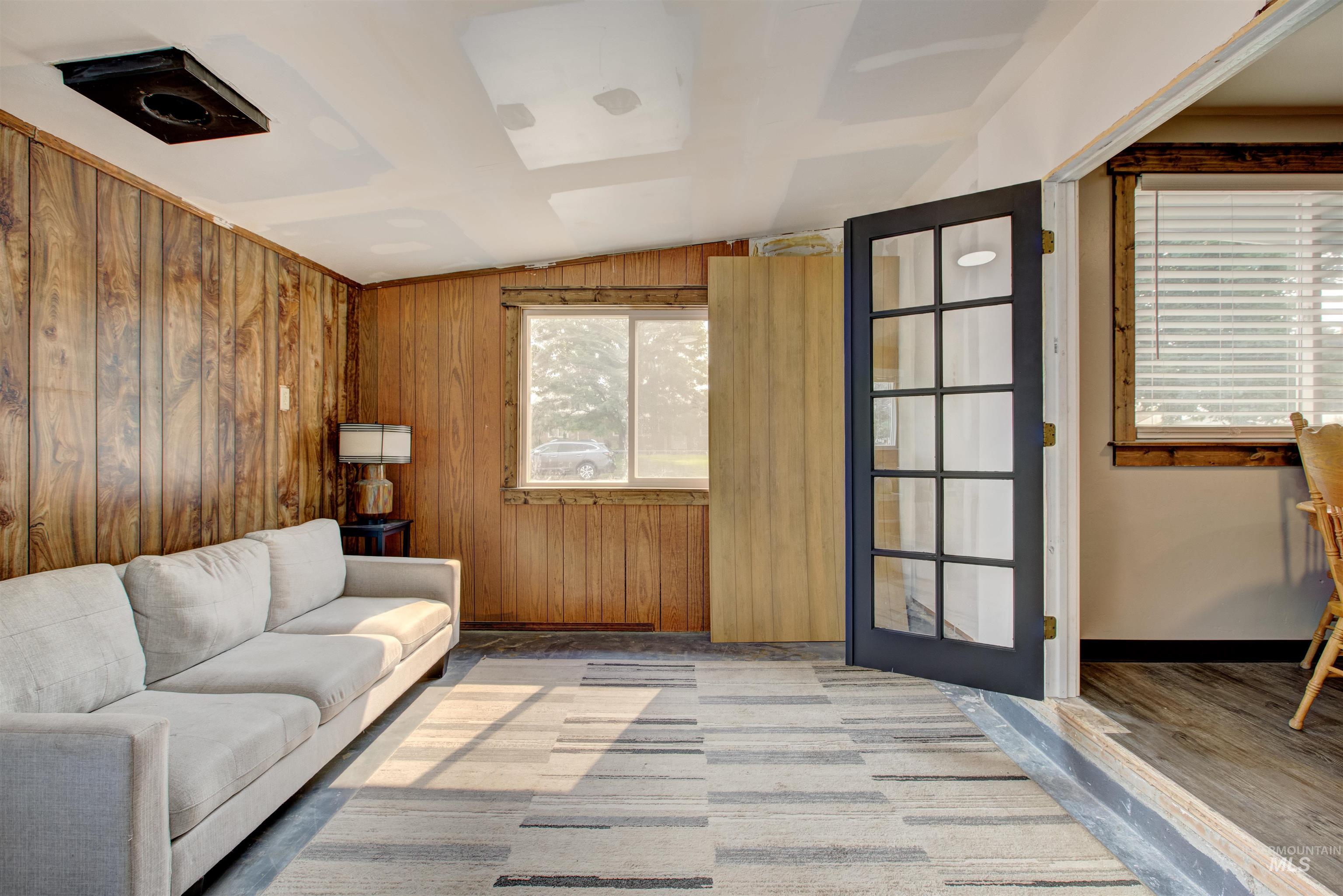 Living room featuring vaulted ceiling and wood walls