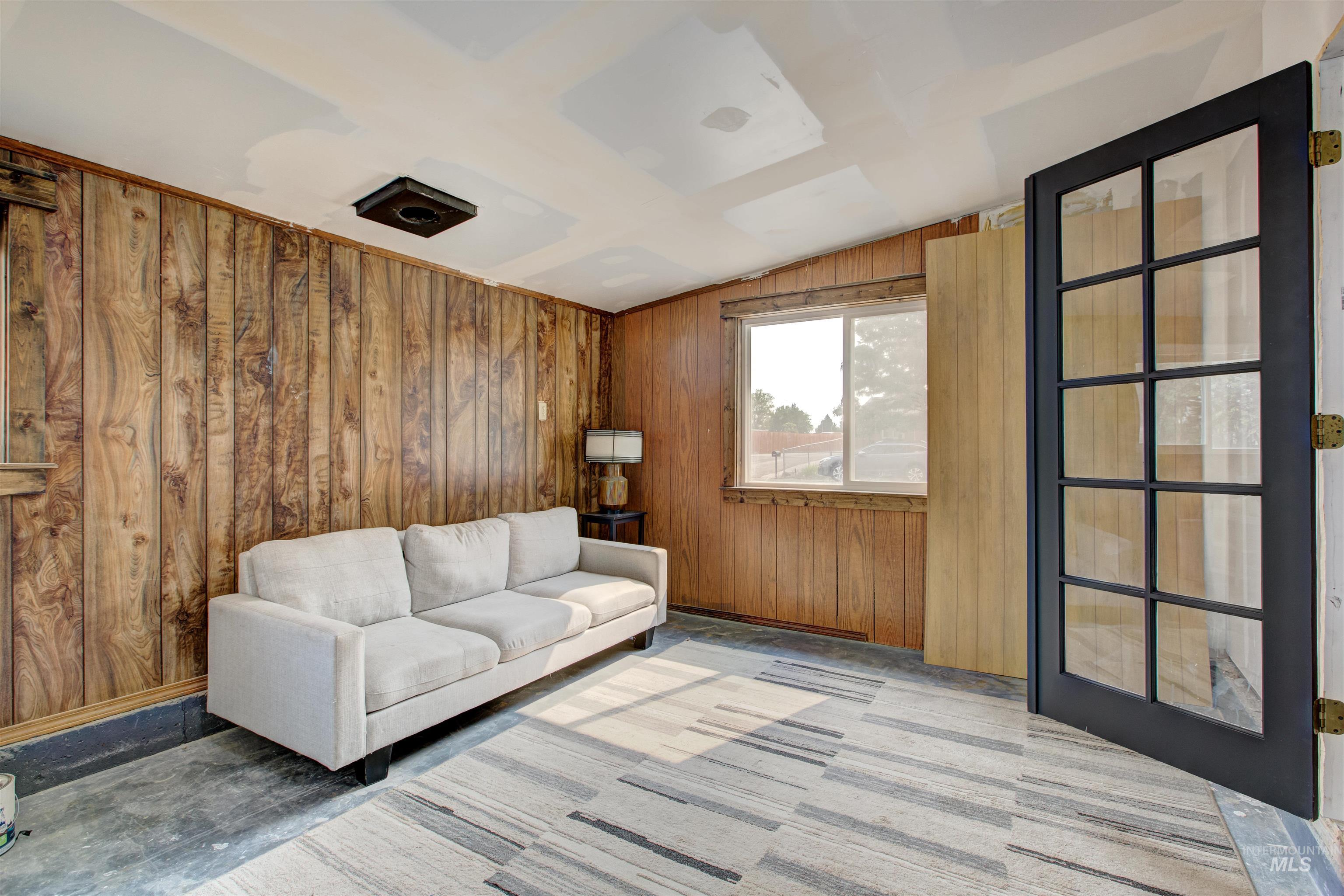 Living room featuring vaulted ceiling and wooden walls