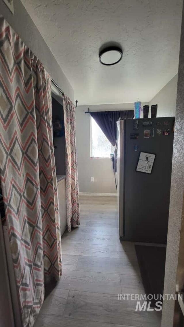 Hall with light wood-style floors and a textured ceiling