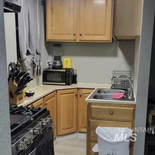 Kitchen featuring light countertops, stainless steel range with gas stovetop, and black microwave