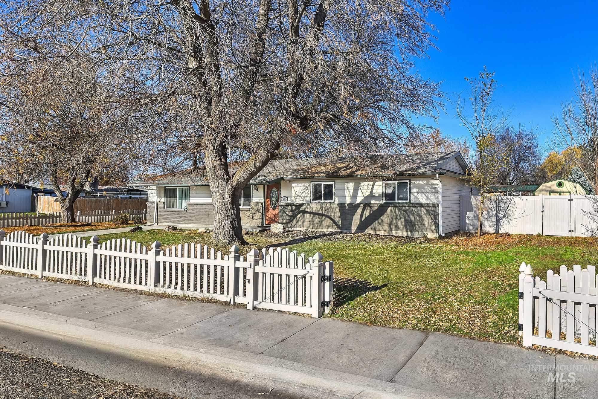 Single story home featuring a gate, a fenced front yard, and brick siding