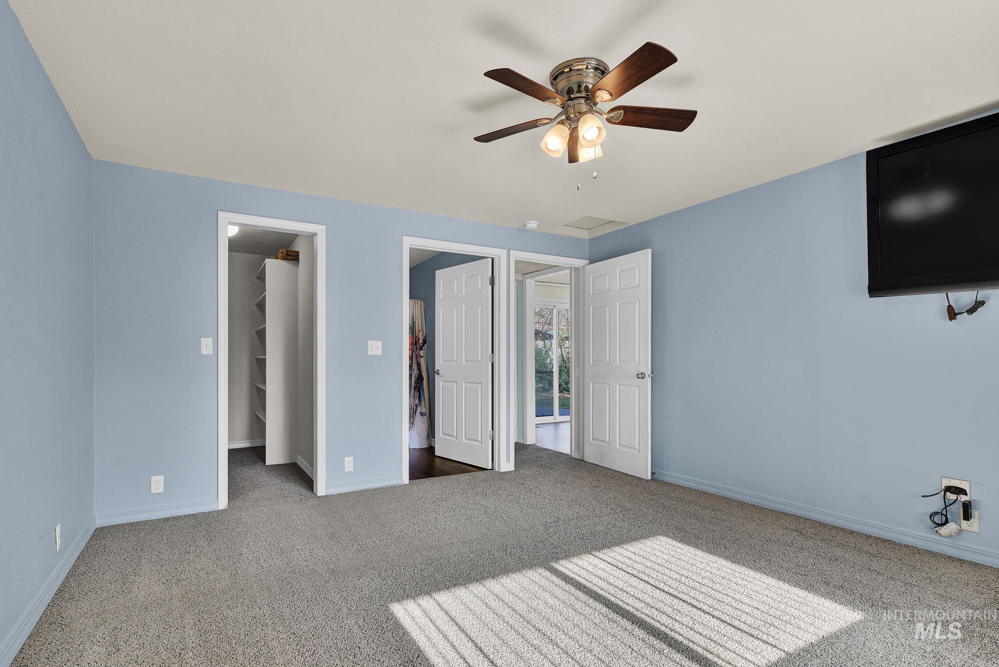 Primary bedroom suite with a spacious walk in closet, new carpet flooring, and ceiling fan