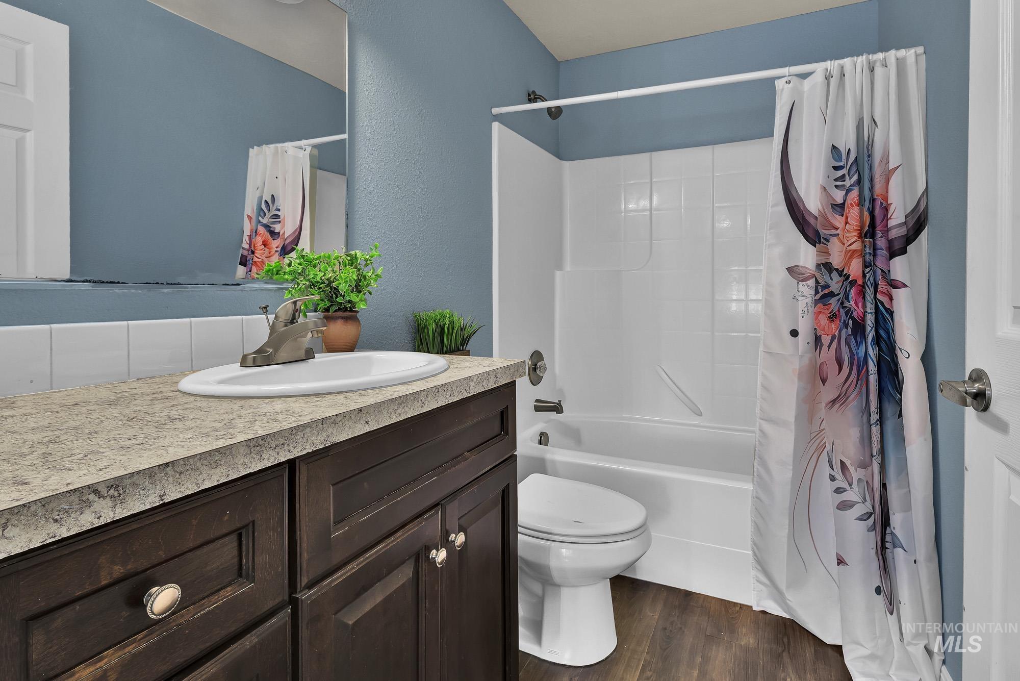 Primary Bathroom with vanity, shower / bath combination with curtain, and laminate wood-type flooring