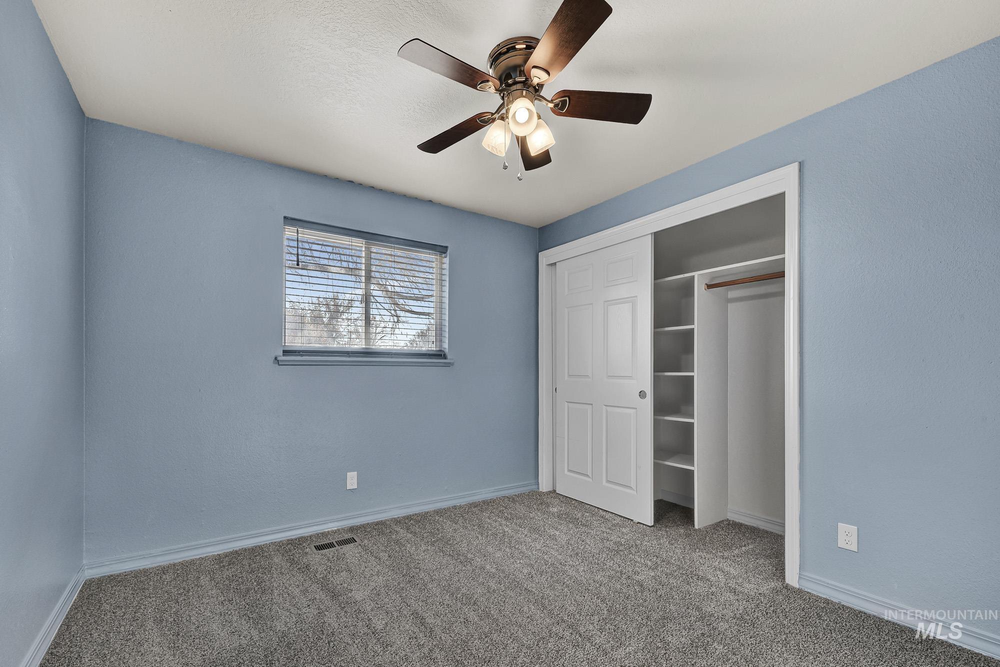 Unfurnished bedroom with new carpet flooring, a ceiling fan, and a closet
