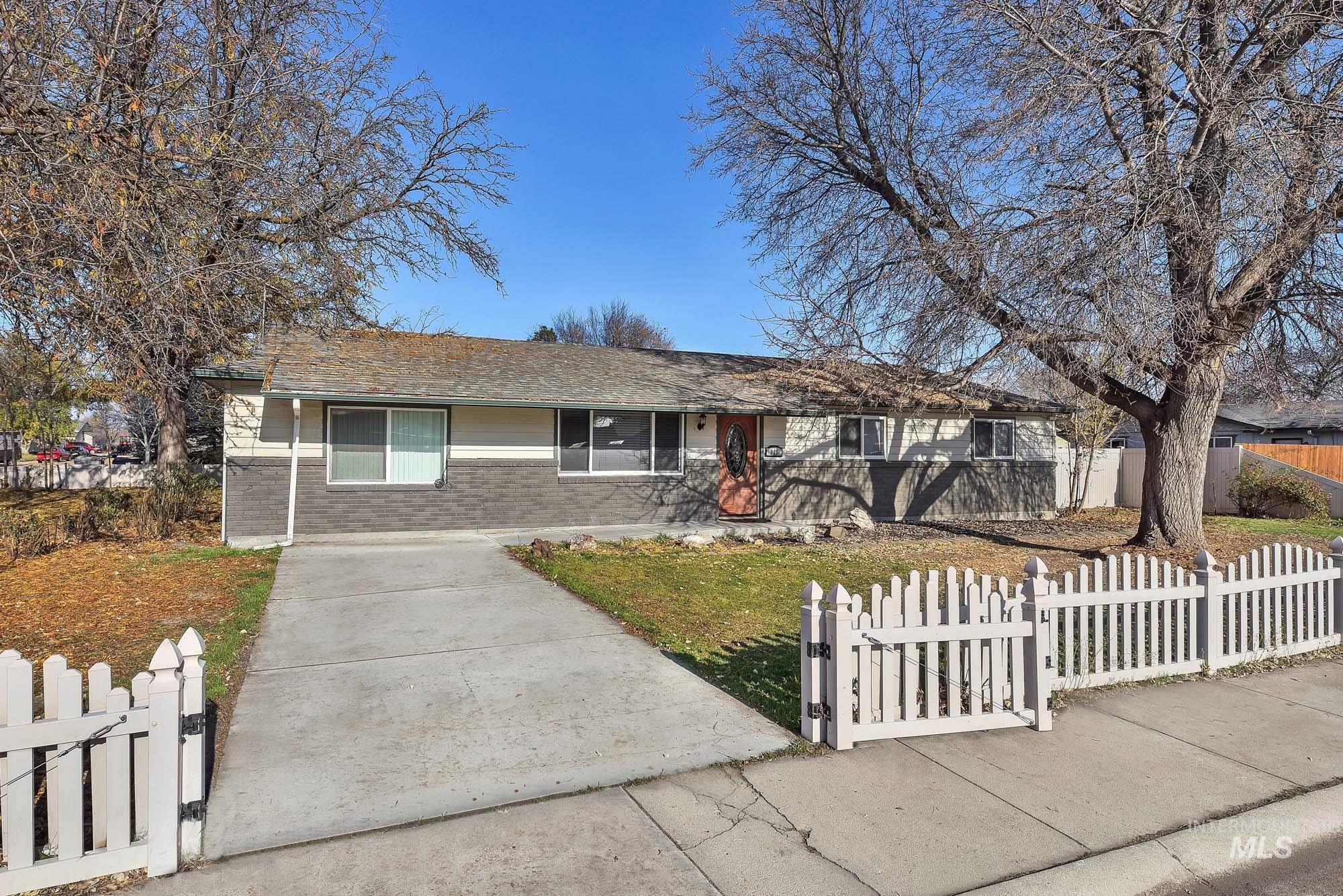 Ranch-style home featuring a fenced front yard, brick siding, a gate, and a shingled roof