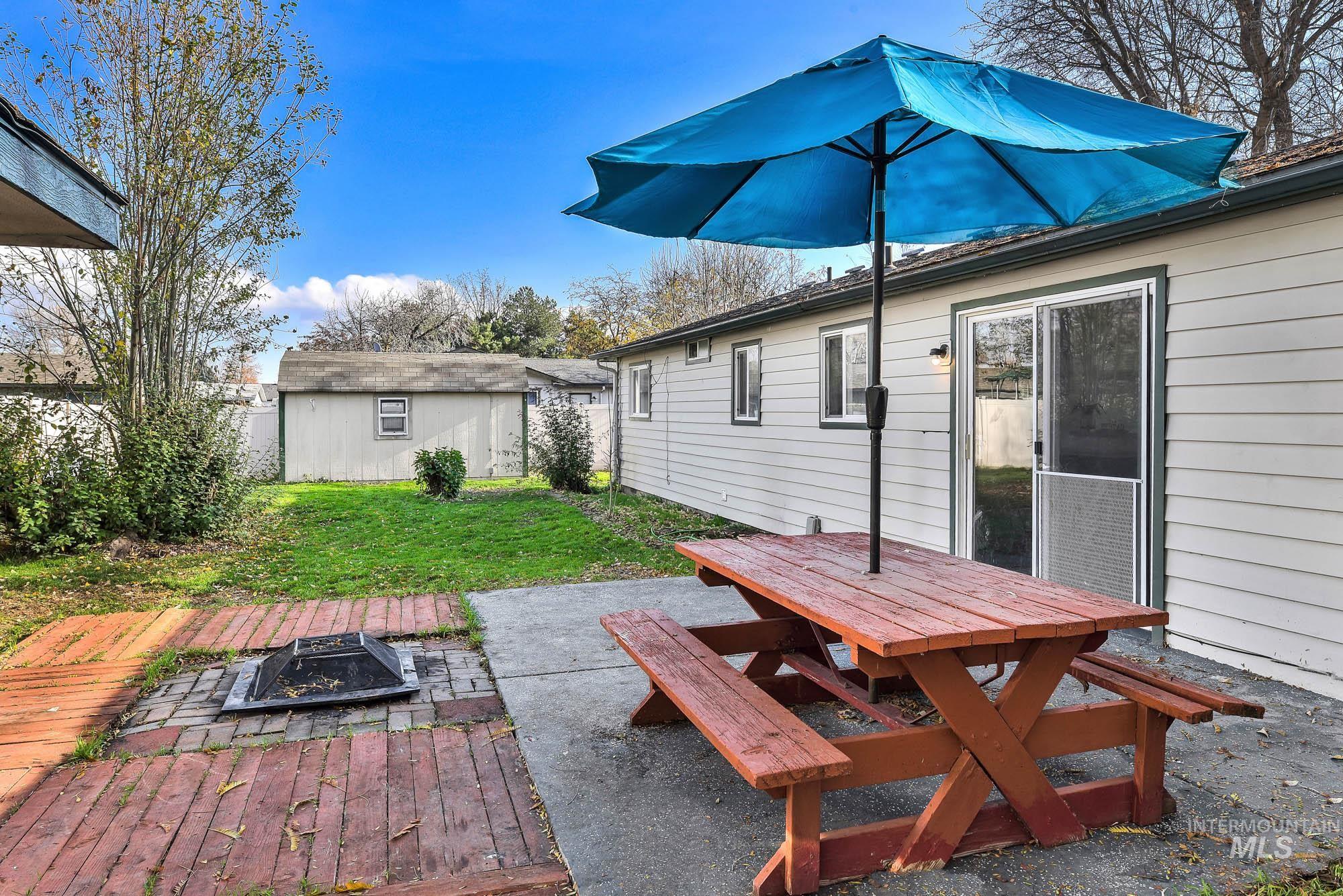 Rear view of property featuring a patio, outdoor dining area, an outdoor fire pit, a fenced backyard, and an outbuilding