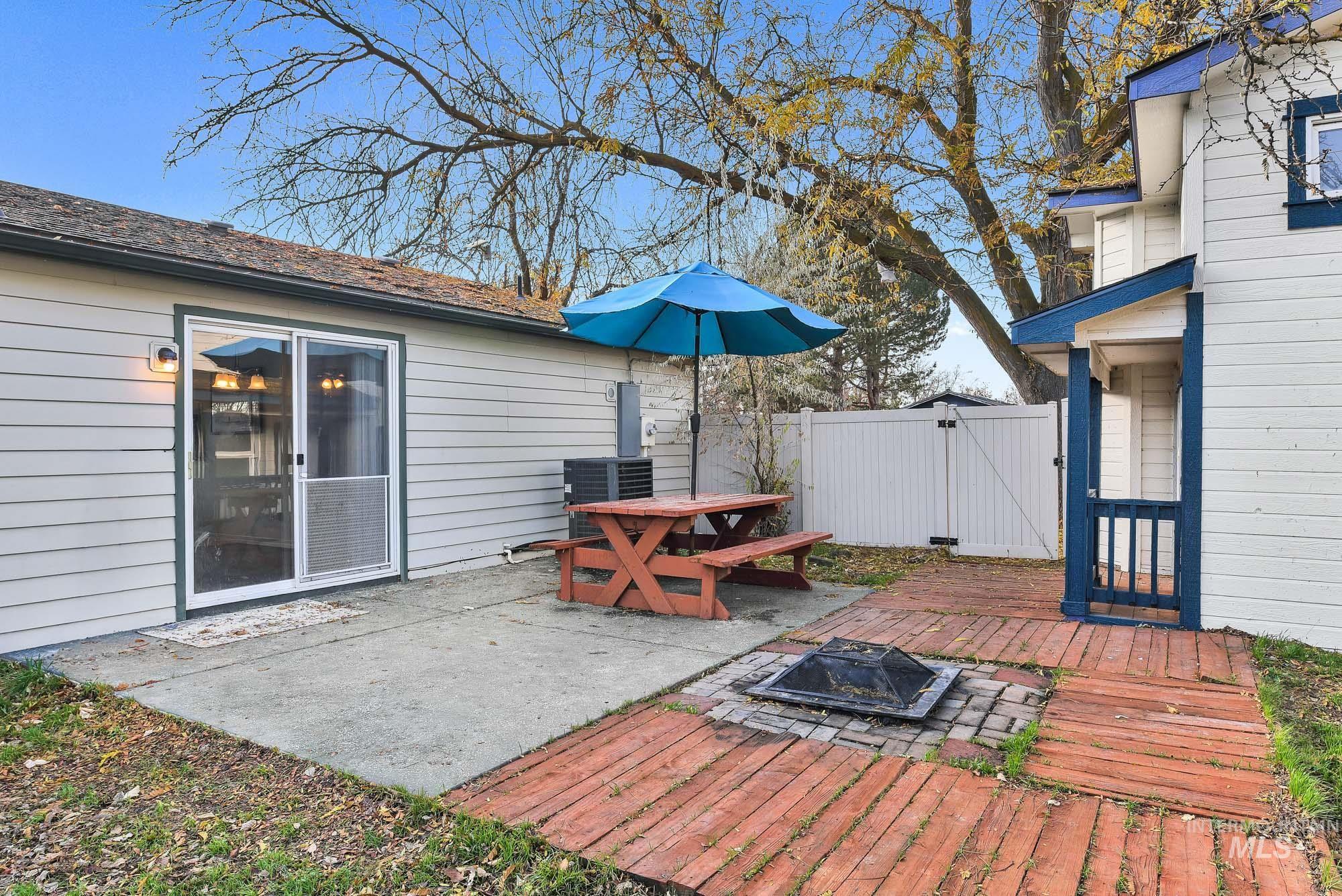 Wooden terrace featuring a fire pit, a patio, and a gate