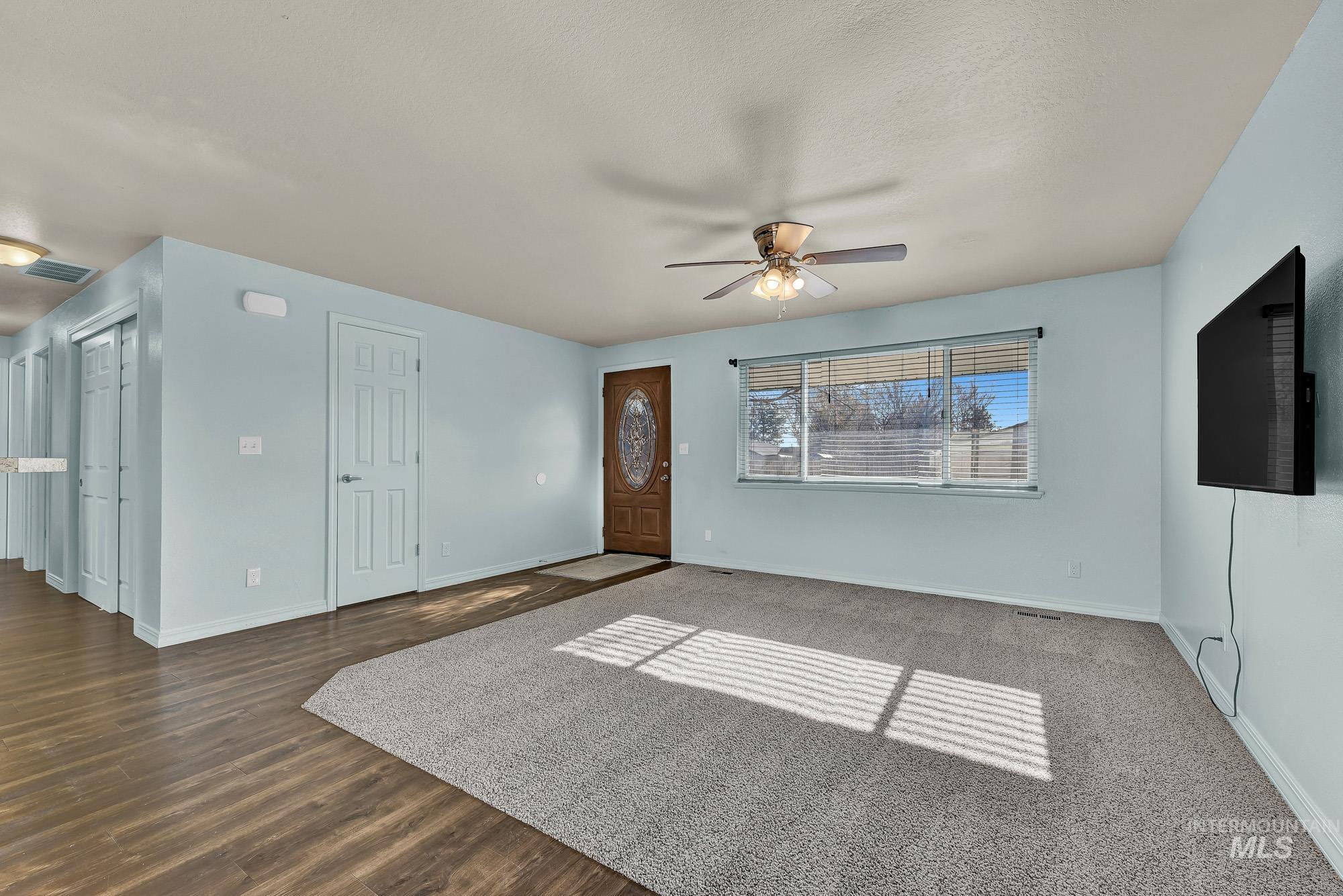 Unfurnished living room featuring ceiling fan, laminate wood like finished floors, and a textured ceiling