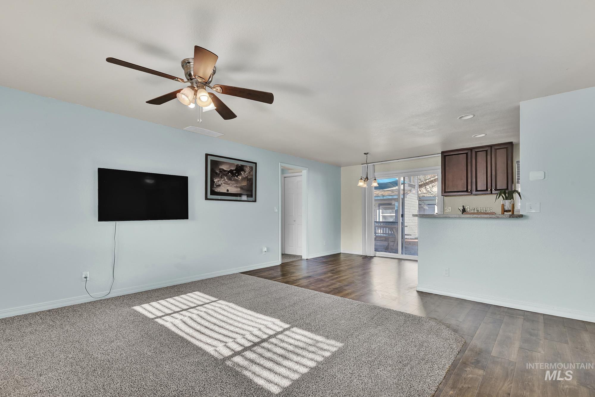 Unfurnished living room featuring new carpet - a  ceiling fan, and laminate wood-like floors
