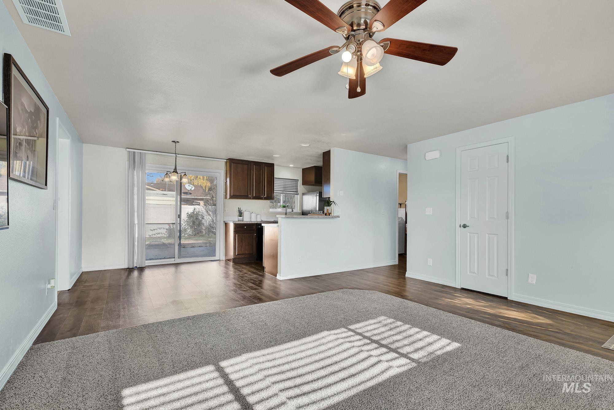 Newly carpeted living room featuring a ceiling fan and laminate wood like finished floors