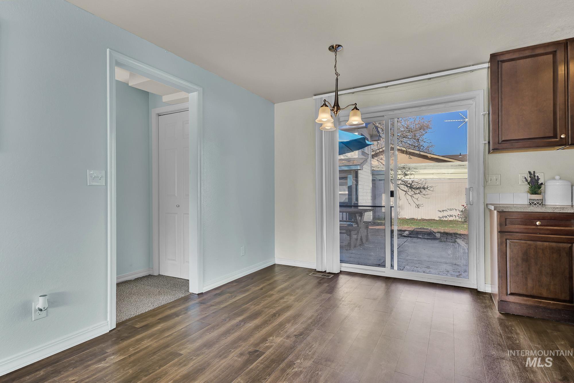 Open dining area featuring a chandelier and laminate wood-style flooring