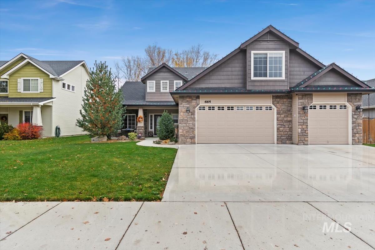 Craftsman inspired home featuring stone siding, driveway, a front lawn, and covered porch