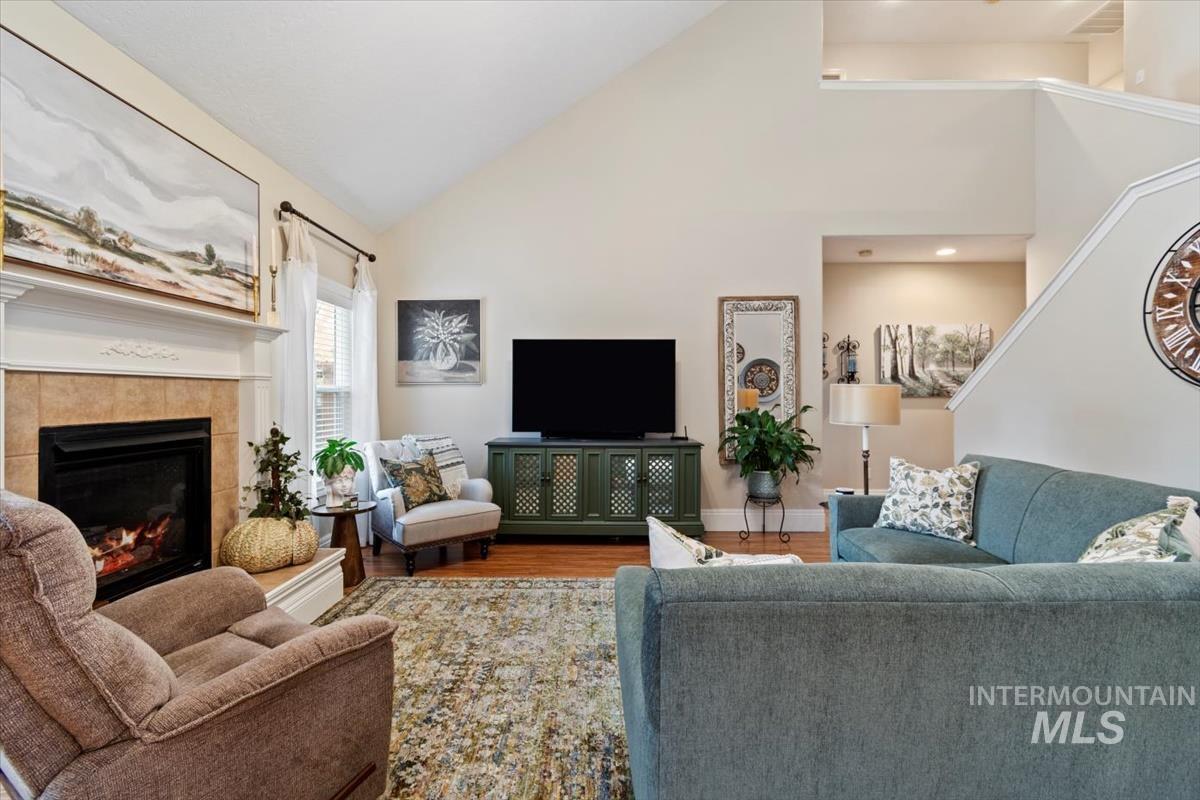 Living area featuring wood finished floors, high vaulted ceiling, and a fireplace