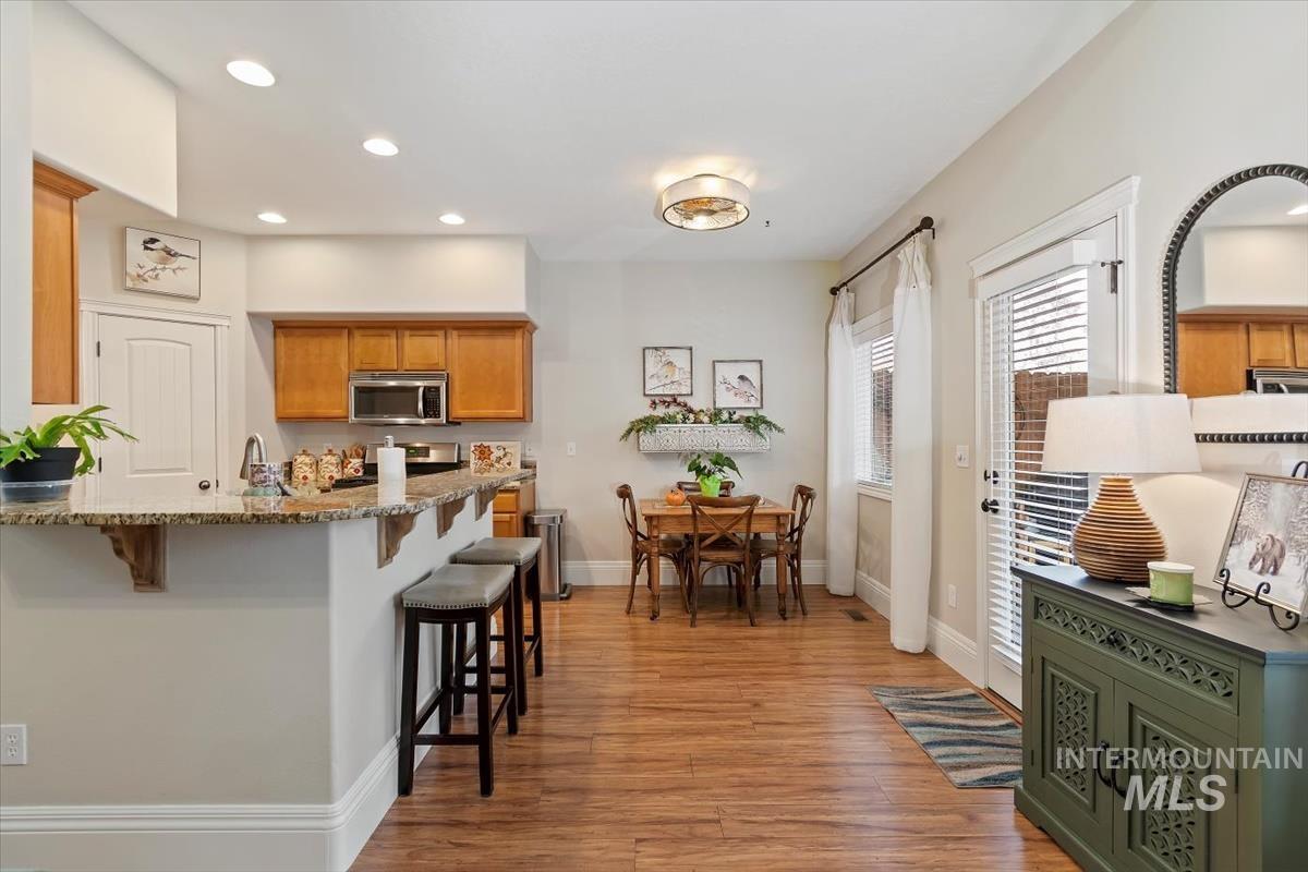Kitchen featuring brown cabinetry, a breakfast bar area, light wood-style flooring, recessed lighting, and stainless steel microwave