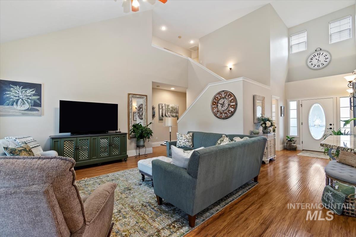 Living room with high vaulted ceiling, wood finished floors, and ceiling fan