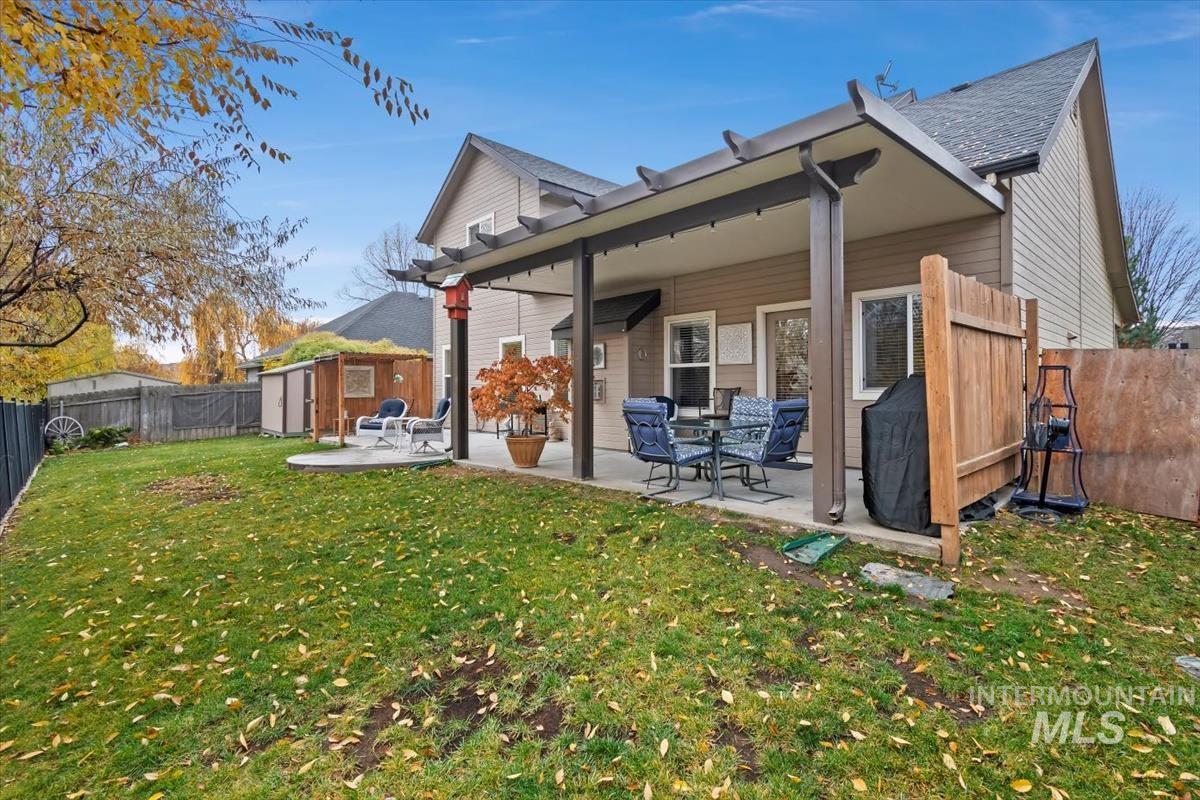 Back of house featuring a fenced backyard, a patio, a storage unit, and a shingled roof