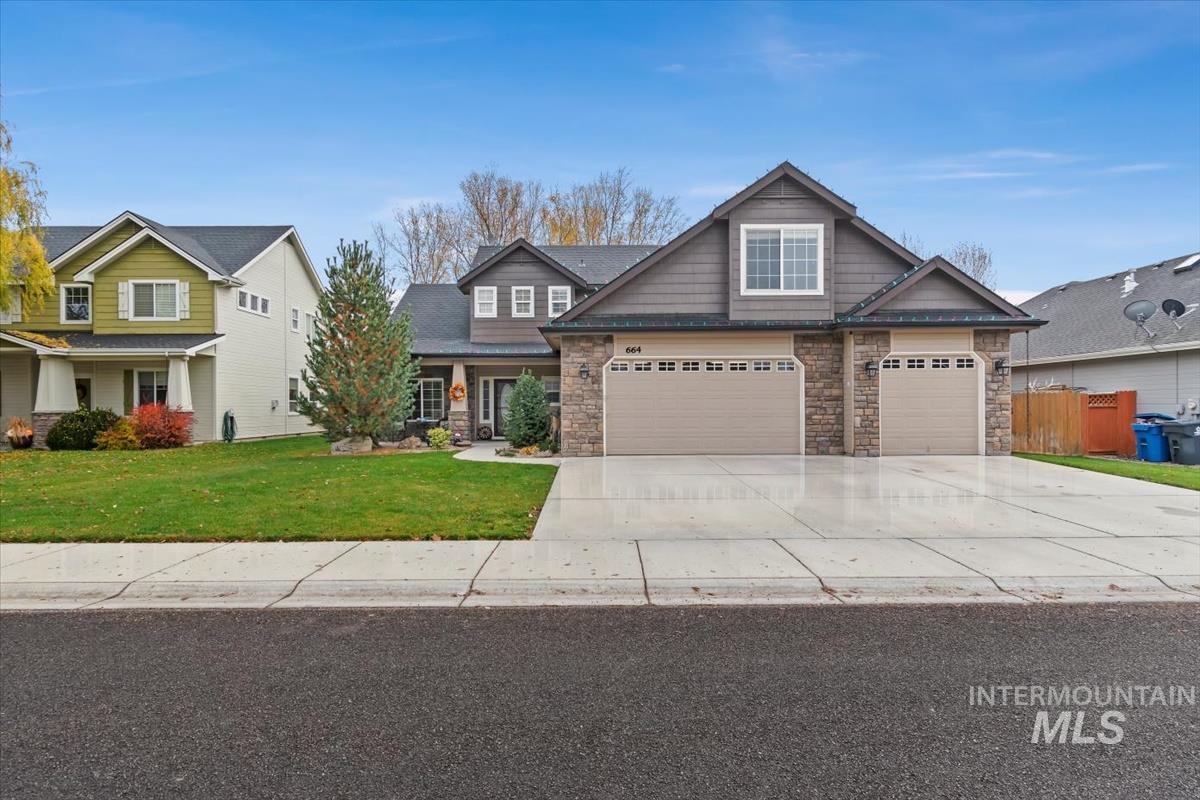 Craftsman inspired home with concrete driveway, stone siding, a front lawn, and covered porch