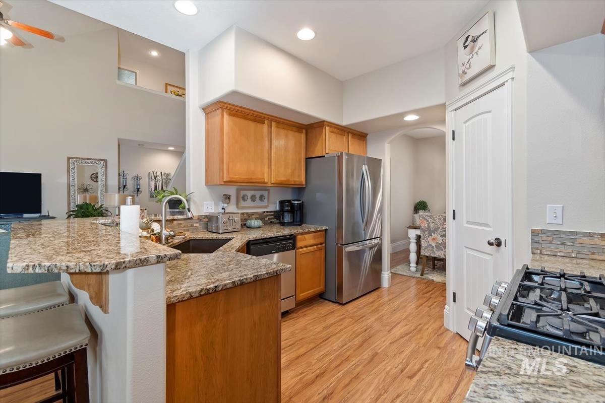 Kitchen featuring a peninsula, light stone countertops, a breakfast bar area, stainless steel appliances, and arched walkways
