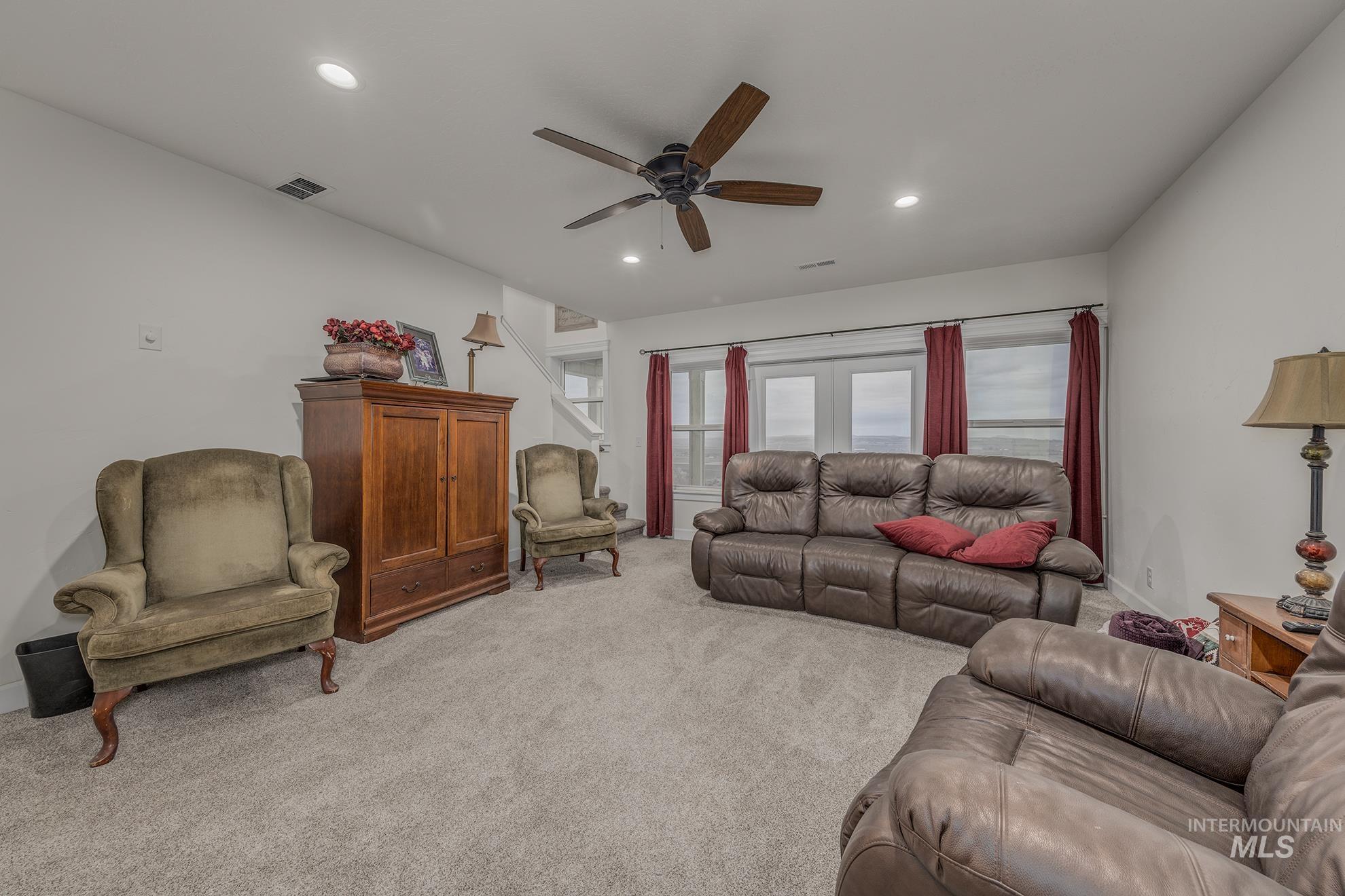 Living area featuring light colored carpet, a ceiling fan, and recessed lighting